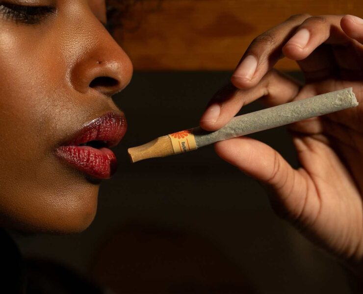 cannabis world news African American woman holding a pre-roll cannabis joint