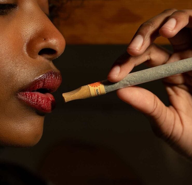 cannabis world news African American woman holding a pre-roll cannabis joint